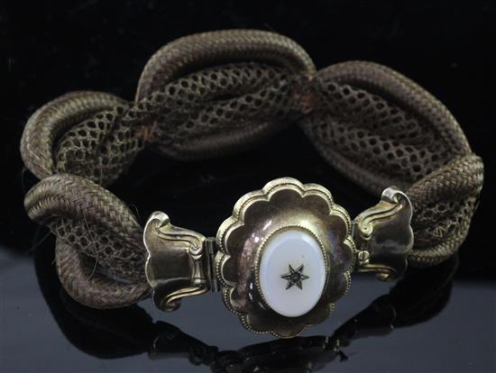 A Victorian plaited hair mourning bracelet with carnelian set gold and base metal oval cusped clasp, 8.5in.